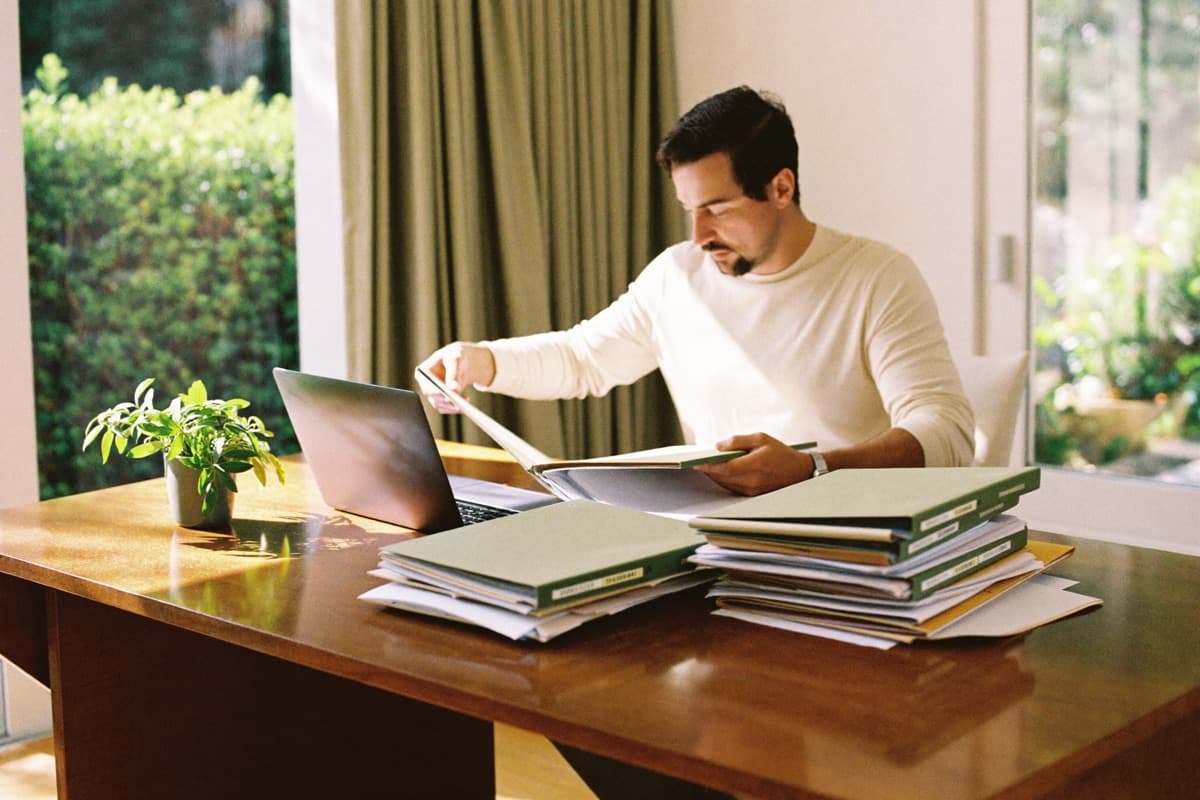 A grant writer working through stacks of client folders at a desk.